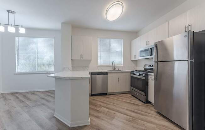 A modern kitchen with stainless steel appliances and wooden flooring.