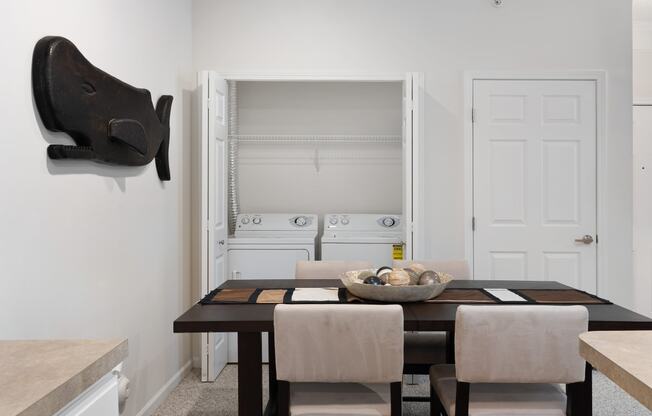 a dining room with a wooden table and chairs and a white kitchen with a sink