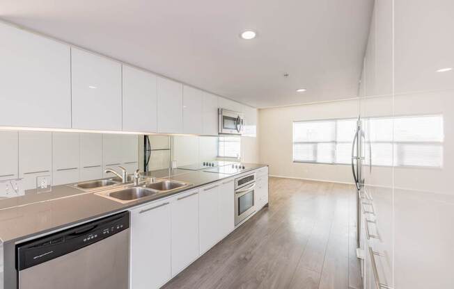 A modern kitchen with white cabinets and stainless steel appliances.