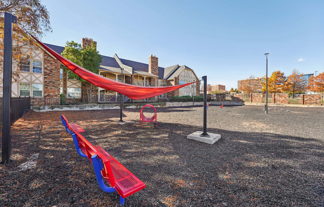 A playground with a red hammock and blue benches.