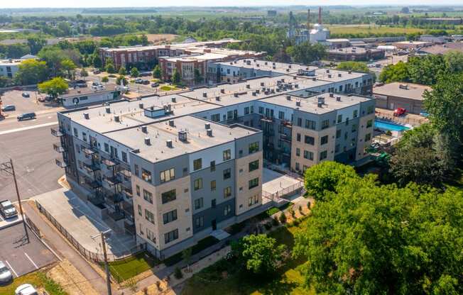 an aerial view of a large apartment building with a pool in the foreground