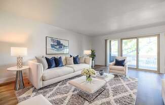 A living room with a white couch, a coffee table, and a painting on the wall.