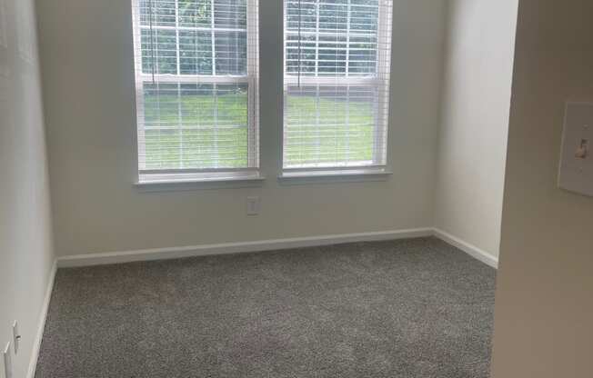 an empty room with two windows and a carpeted floor