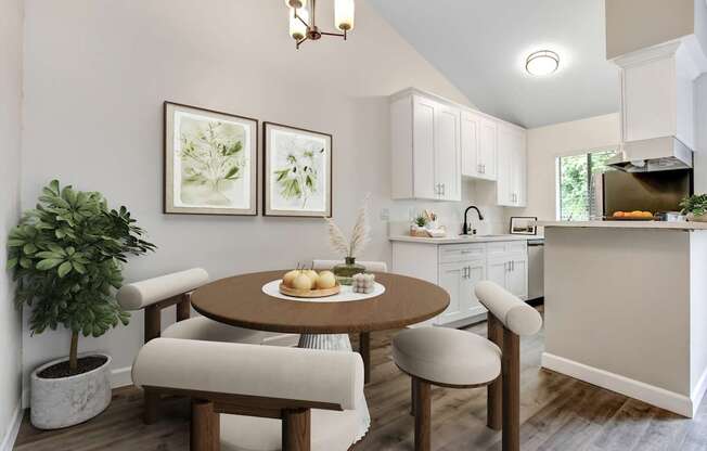 A kitchen with a table and chairs in the foreground and a plant in a pot.