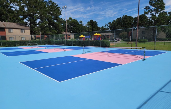 a group of tennis courts are painted in blue and pink