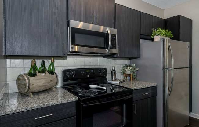 a kitchen with dark cabinets and stainless steel appliances