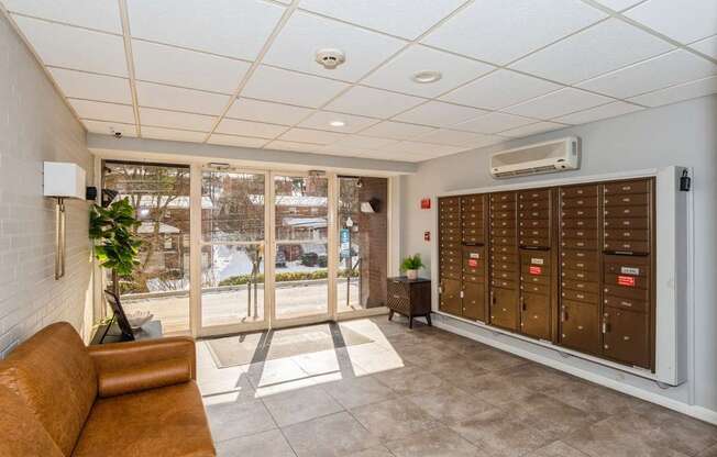 A room with a brown couch and a wall of mailboxes.