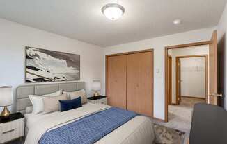 a bedroom with a bed and a closet and a door to a bathroom. Fargo, ND Oxford Apartments