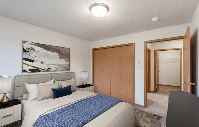 a bedroom with a bed and a closet and a door to a bathroom. Fargo, ND Oxford Apartments