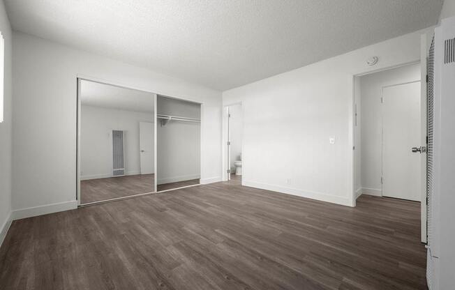 A large empty room with wooden floors and white walls.
