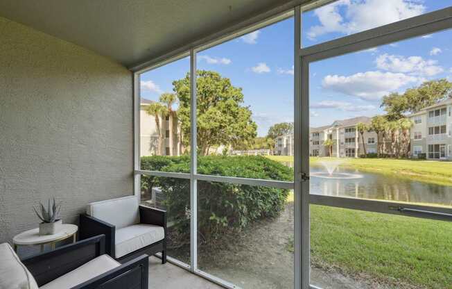 A patio with a table and chairs overlooks a grassy area and a pond.