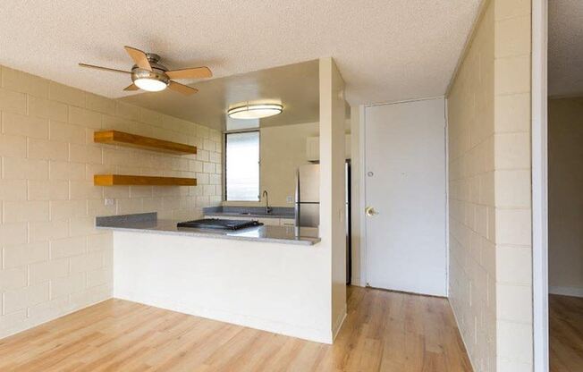 an empty room with a kitchen and a ceiling fan at Palms of Kilani Apartments, Hawaii