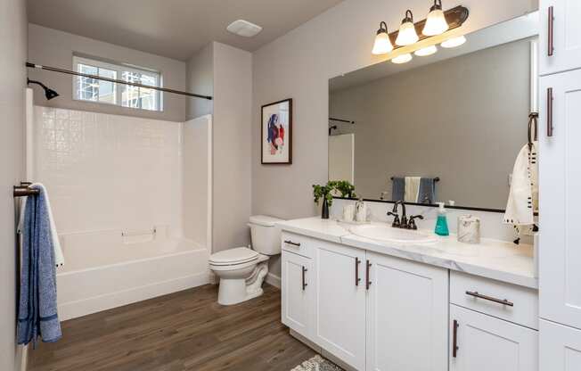 a bathroom with white cabinets and a white bathtub