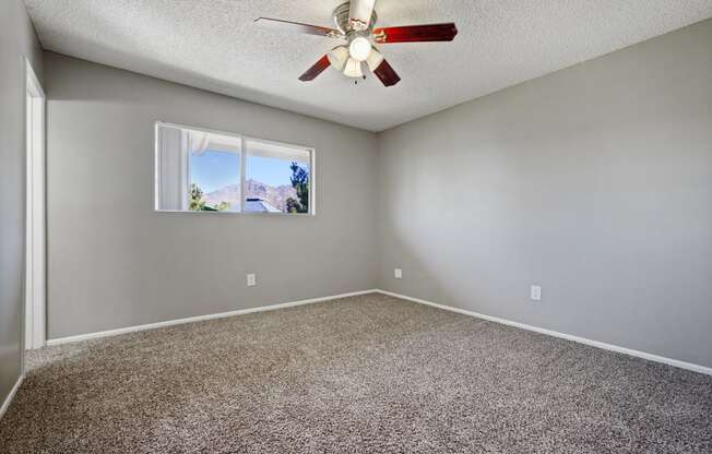 an empty room with a ceiling fan and a window