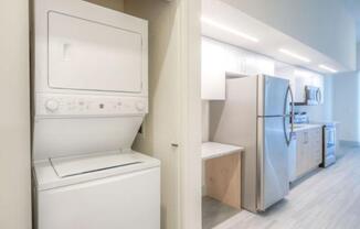 View of a stacked washer and dryer within a side space tucked in the wall near the kitchen at Lofts at South Lake, Clermont, FL
