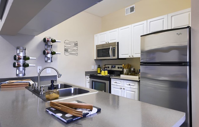 A kitchen with a stainless steel refrigerator and a stainless steel sink.