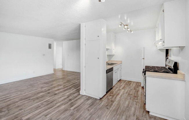 an empty kitchen and living room with white walls and wood floors