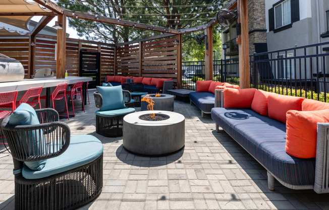 a lounge area with couches and chairs around a fire pit