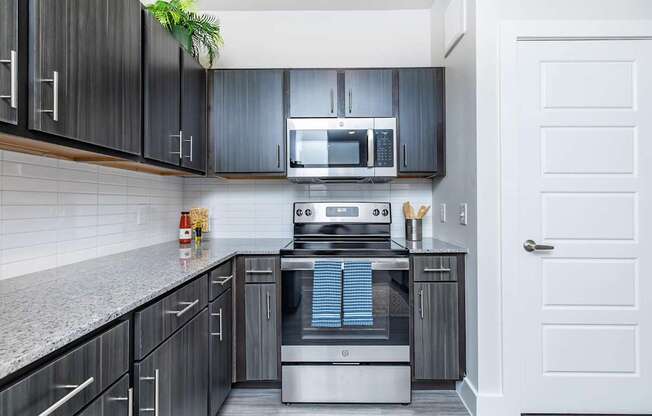 A modern kitchen with dark wood cabinets and stainless steel appliances.
