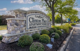 Clinton Place Apartment Homes sign with a stone pillar and bushes.