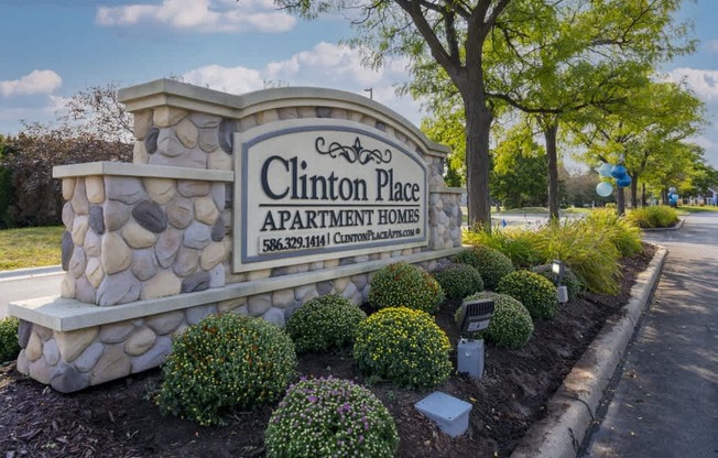 Clinton Place Apartment Homes sign with a stone pillar and bushes.