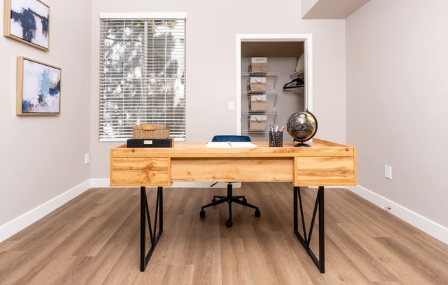 a home office with a wooden desk and a large window