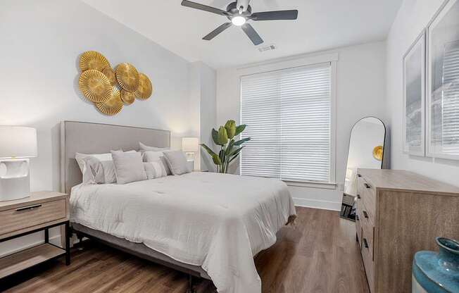 A bedroom with a bed, dresser, and ceiling fan.
