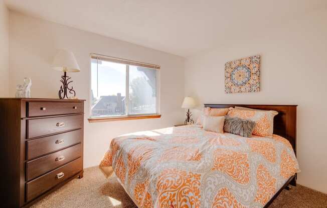 Bedroom in the two-bedroom model unit at Olde English Village, featuring a comfortable bed and soft lighting.