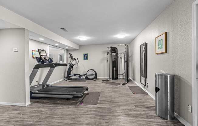 a gym with treadmills and exercise equipment in a home with white walls