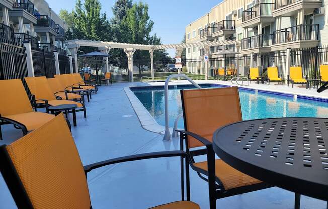 a poolside patio with chairs and tables at an apartment building