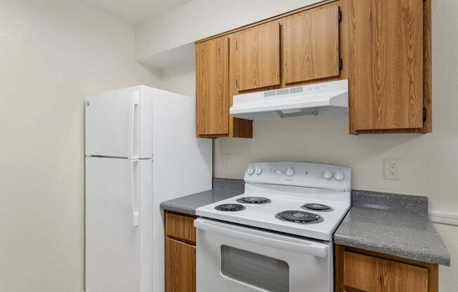A white refrigerator and stove in a kitchen with wooden cabinets at Urban WalkApartments on 6th Avenue, Arizona