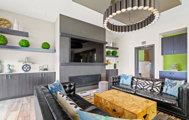 a living room with black leather couches and a wooden coffee table