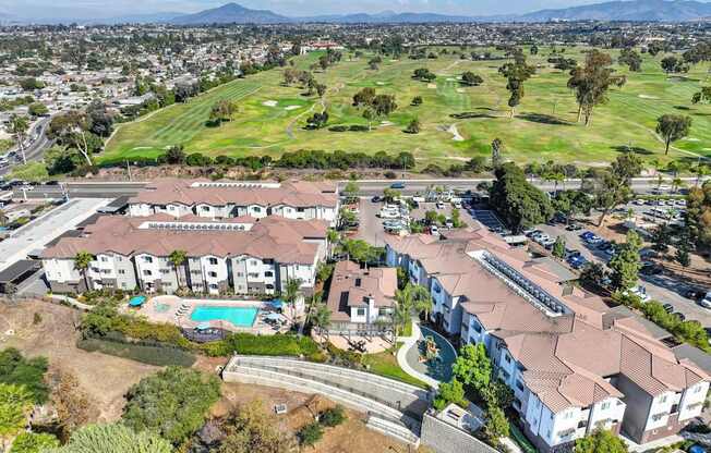 A large apartment complex with a pool and a golf course in the background.