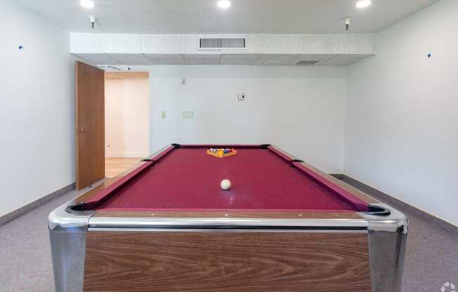 a red pool table in a room with a ball on it