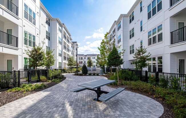 A sunny day at a residential complex with a picnic table in the middle of a paved walkway.