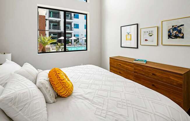 A bedroom with a bed, pillows, a nightstand, and pictures on the wall.