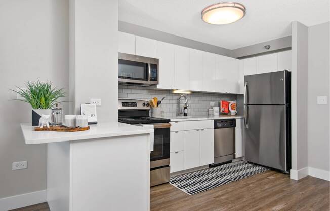 a white kitchen with stainless steel appliances and a counter top