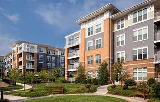 an exterior view of an apartment complex with benches and grass