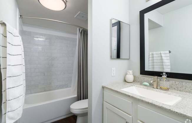A white bathroom with a toilet, sink, and mirror.