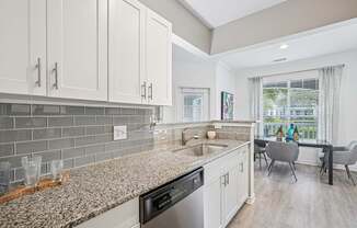A kitchen with a granite countertop and a dining table with chairs.