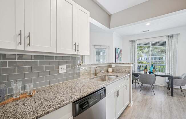 A kitchen with a granite countertop and a dining table with chairs.