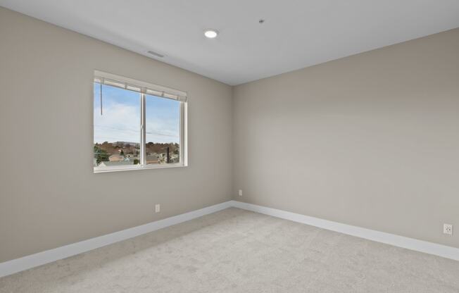 a bedroom with gray walls and a large window
