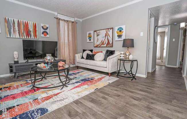 Model living room with a white couch and a glass coffee table at Maplewood apartments in Shreveport, LA.