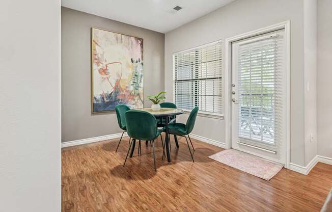 A dining room with a green table and chairs.