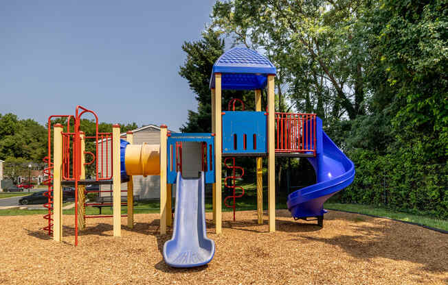 a playground with a blue and red swing set and a yellow and red slide