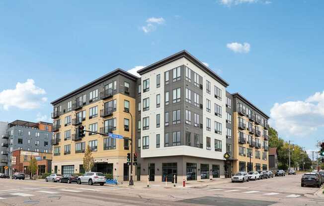 A street view of a multi-story building with cars parked in front.