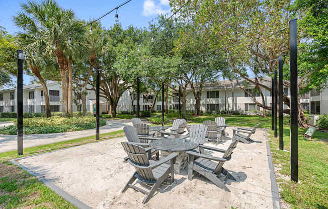 a sandy picnic area with tables and chairs in a park
