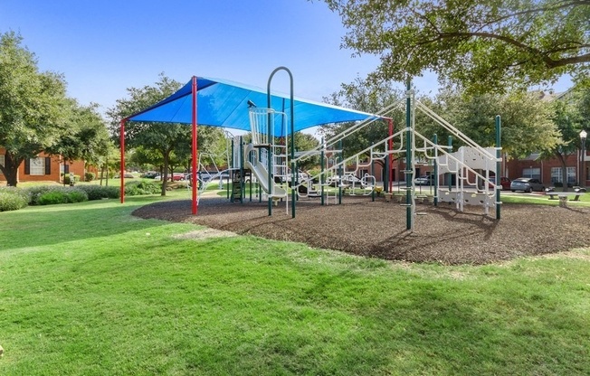 Playground on sand surrounded by well kept grass