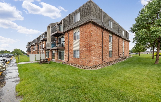A red brick building with a green lawn in front.