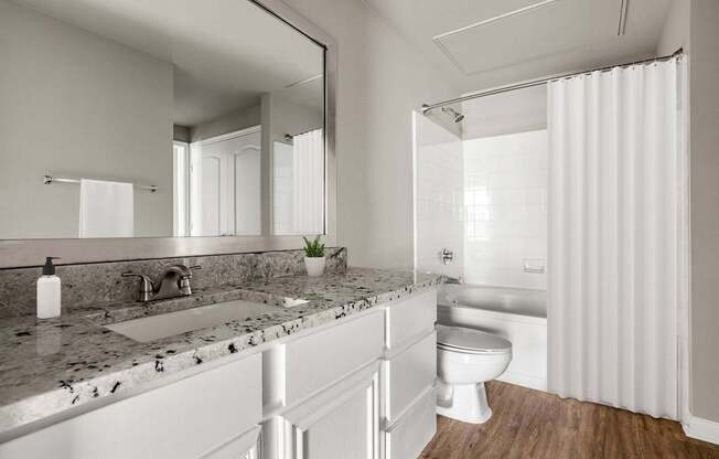 A modern bathroom with a marble countertop and white fixtures.
